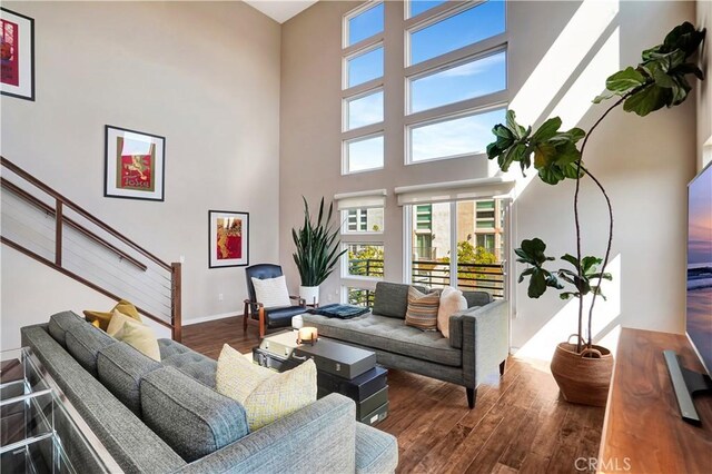 1508 W Artesia Unit H, Gardena, CA 90248 - living area featuring wood finished floors, a towering ceiling, stairway, and baseboards