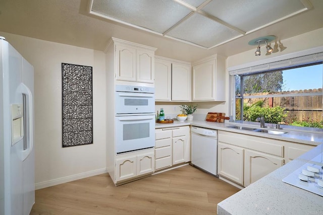 2935 Via Emerado, Carlsbad, CA 92009 - kitchen featuring white appliances, white cabinets, light wood-style flooring, and a sink