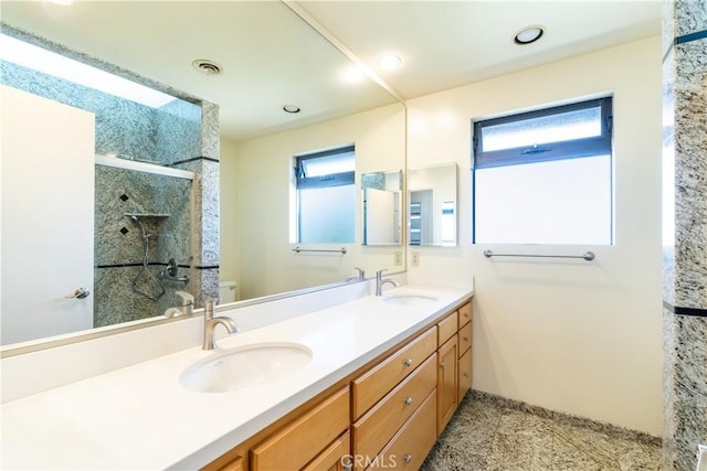 bathroom with a shower stall, toilet, double vanity, recessed lighting, and baseboards