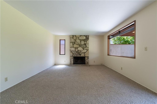 unfurnished living room featuring plenty of natural light, a fireplace, and carpet floors