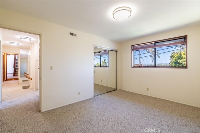 unfurnished bedroom featuring light carpet, a closet, and baseboards
