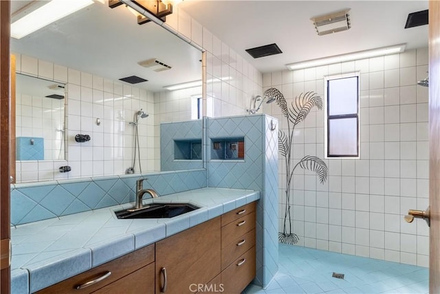 2405 Tustin Ave, Costa Mesa, CA 92627 - bathroom featuring tiled shower, vanity, tasteful backsplash, tile walls, and tile patterned flooring