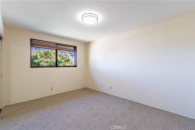 spare room with light colored carpet and baseboards