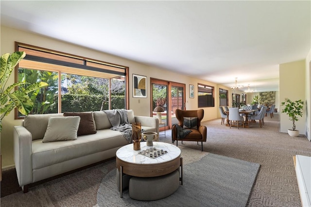 carpeted living area featuring healthy amount of natural light and a chandelier