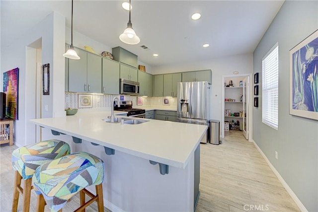 43075 Beamer Ct, Temecula, CA 92592 - kitchen with appliances with stainless steel finishes, a kitchen bar, a peninsula, light countertops, and tasteful backsplash