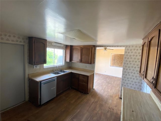 kitchen with wallpapered walls, dishwasher, dark wood finished floors, light countertops, and a sink