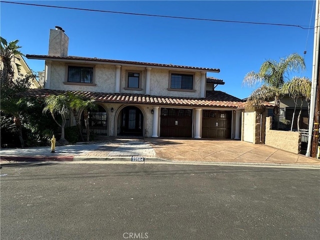 22564 Inspiration Pt, Canyon Lake, CA 92587 - mediterranean / spanish house with stucco siding, a chimney, driveway, a tile roof, and a garage