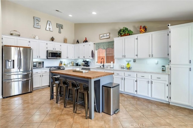 25515 Mountain Springs St, Menifee, CA 92584 - kitchen featuring stainless steel appliances, vaulted ceiling, wooden counters, white cabinetry, and a kitchen breakfast bar
