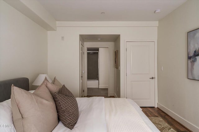 bedroom with wood finished floors, baseboards, and connected bathroom