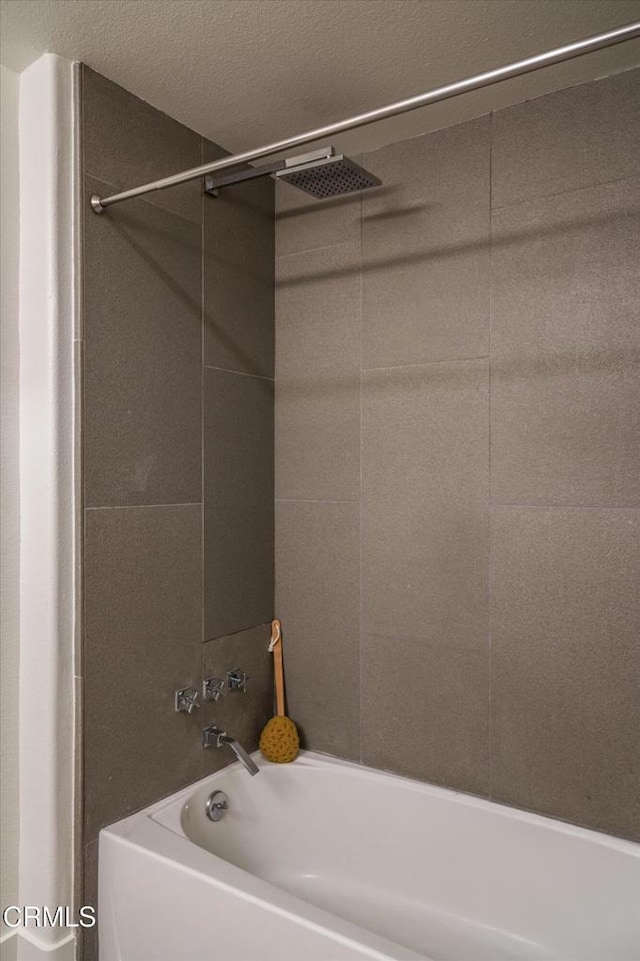 bathroom with a textured ceiling and shower / tub combination