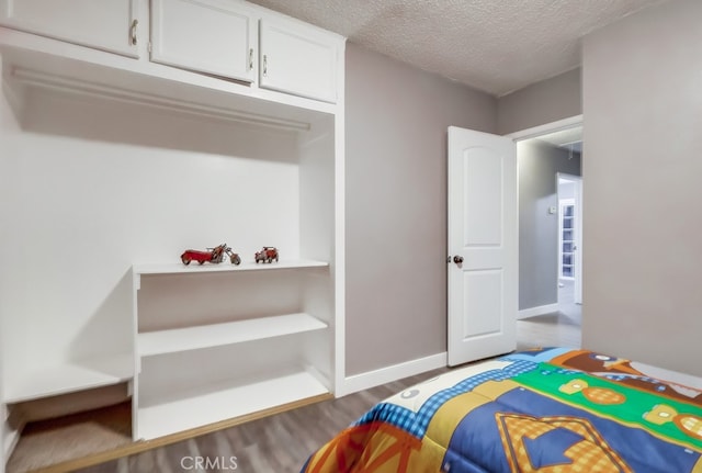 bedroom featuring wood finished floors, a textured ceiling, and baseboards