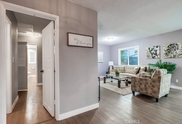 living room featuring wood finished floors, a textured ceiling, and baseboards