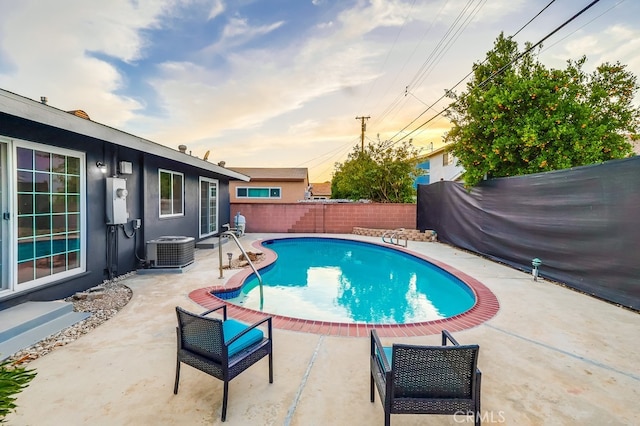 pool at dusk with a fenced backyard, cooling unit, and a patio