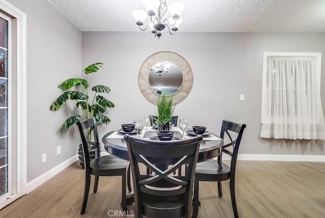 dining area with a textured ceiling, a chandelier, wood finished floors, and baseboards