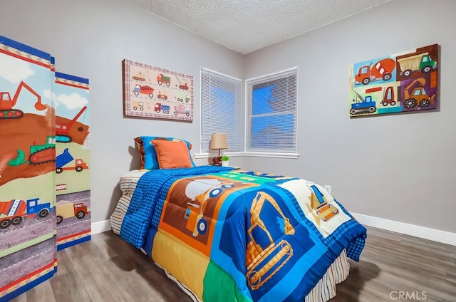 bedroom with wood finished floors, a textured ceiling, and baseboards