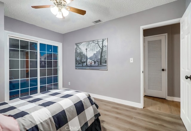bedroom featuring wood finished floors, a textured ceiling, baseboards, and ceiling fan