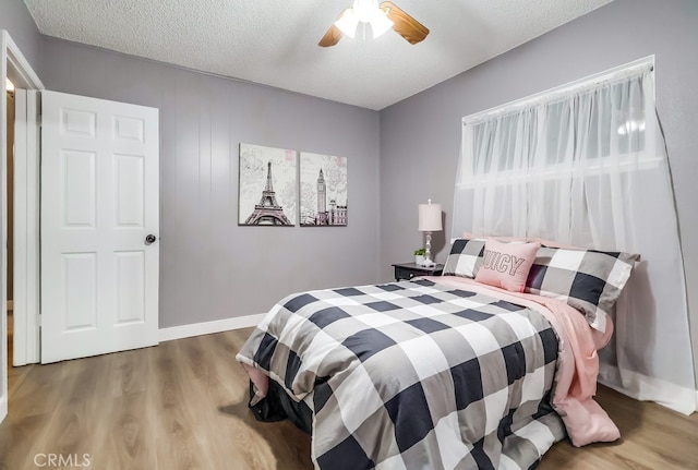 bedroom featuring wood finished floors, a textured ceiling, a ceiling fan, and baseboards