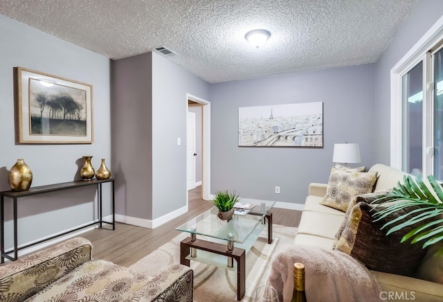 living area with wood finished floors, a textured ceiling, and baseboards