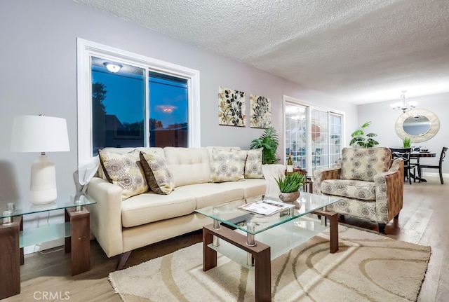 living room featuring wood finished floors, a textured ceiling, baseboards, and a chandelier