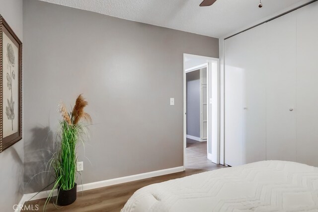 bedroom featuring wood finished floors, a closet, baseboards, and a ceiling fan