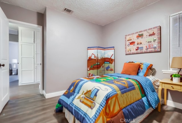 bedroom featuring wood finished floors, a textured ceiling, and baseboards