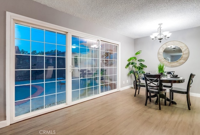 dining room featuring a chandelier, wood finished floors, baseboards, and a textured ceiling