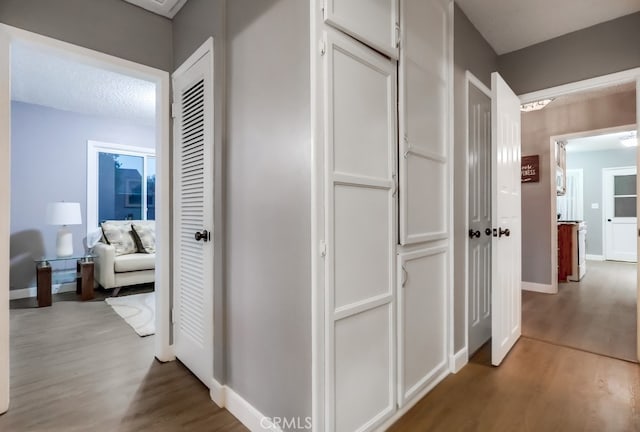 hallway featuring wood finished floors and baseboards