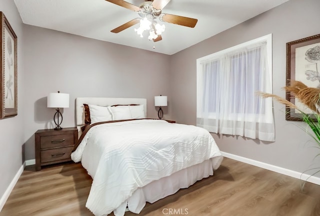 bedroom featuring baseboards, wood finished floors, and ceiling fan