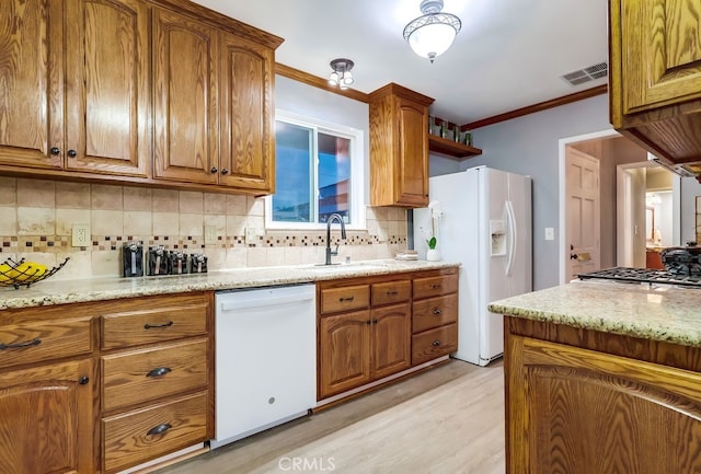 kitchen with white appliances, a sink, light wood-type flooring, brown cabinets, and ornamental molding