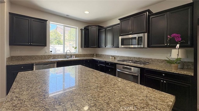 14247 Symphony Ct, Eastvale, CA 92880 - kitchen featuring stainless steel appliances, a sink, recessed lighting, light stone countertops, and dark cabinetry