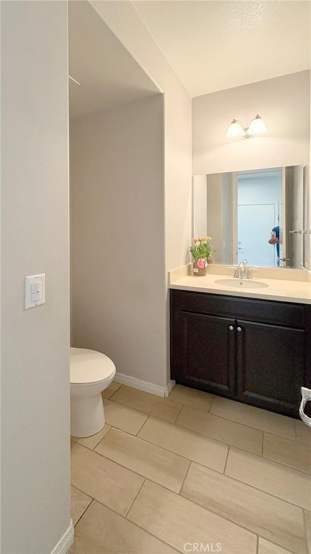14247 Symphony Ct, Eastvale, CA 92880 - half bathroom featuring vanity, toilet, baseboards, and tile patterned flooring