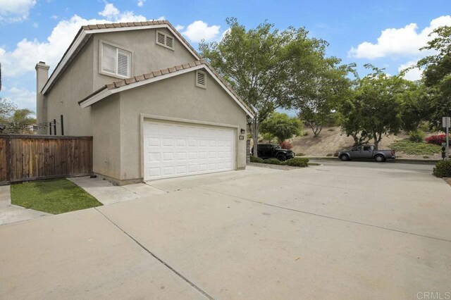 1444 Wooden Valley St, Chula Vista, CA 91913 - view of side of home with stucco siding, driveway, a chimney, and an attached garage