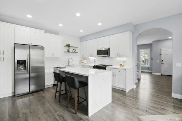 1444 Wooden Valley St, Chula Vista, CA 91913 - kitchen featuring appliances with stainless steel finishes, arched walkways, a center island, tasteful backsplash, and white cabinetry