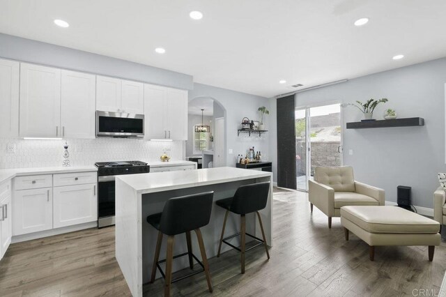 1444 Wooden Valley St, Chula Vista, CA 91913 - kitchen with range with gas stovetop, stainless steel microwave, arched walkways, a kitchen island, and tasteful backsplash