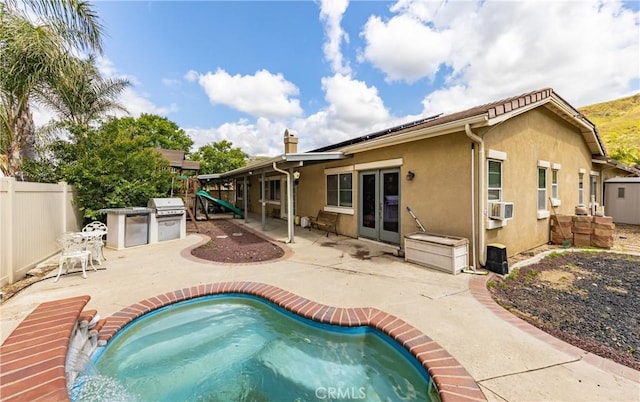 7840 La Cresta St, Highland, CA 92346 - rear view of house with stucco siding, a patio, a fenced backyard, roof mounted solar panels, and a playground
