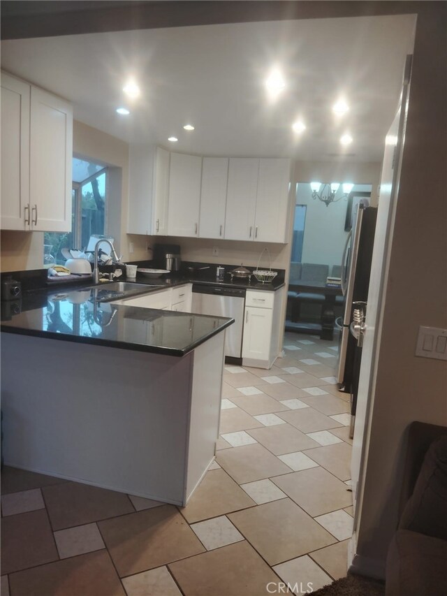 10228 Via Pavon, Moreno Valley, CA 92557 - kitchen with stainless steel appliances, a peninsula, dark countertops, white cabinetry, and a sink