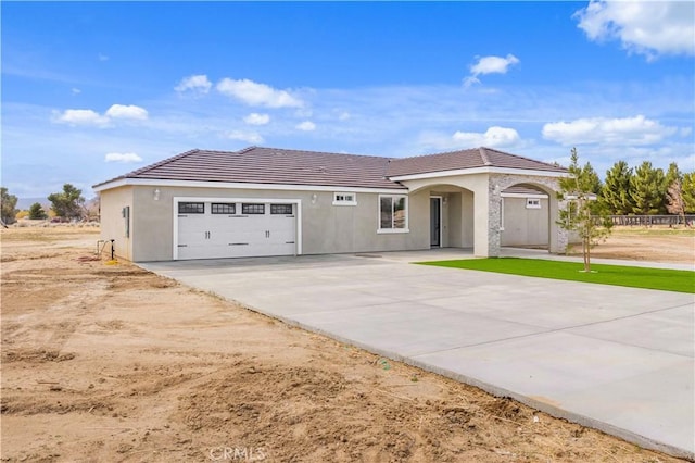 view of front of home featuring a tiled roof, stucco siding, driveway, and an attached garage