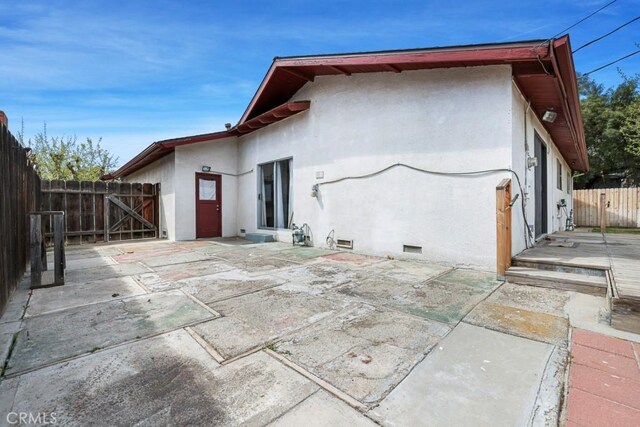 459 Roosevelt St, Coalinga, CA 93210 - rear view of house with stucco siding, a patio area, fence, a gate, and crawl space