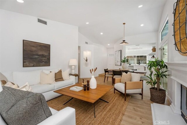 8 Galanto, Irvine, CA 92614 - living area with light wood-style floors, vaulted ceiling, a fireplace with raised hearth, and recessed lighting