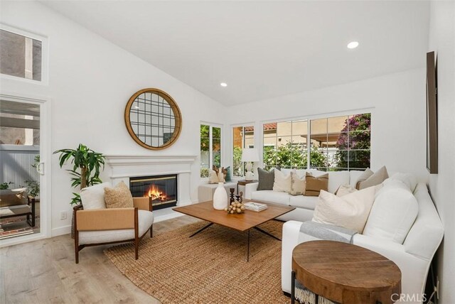 8 Galanto, Irvine, CA 92614 - living room with healthy amount of natural light, lofted ceiling, light wood-style flooring, recessed lighting, and a glass covered fireplace