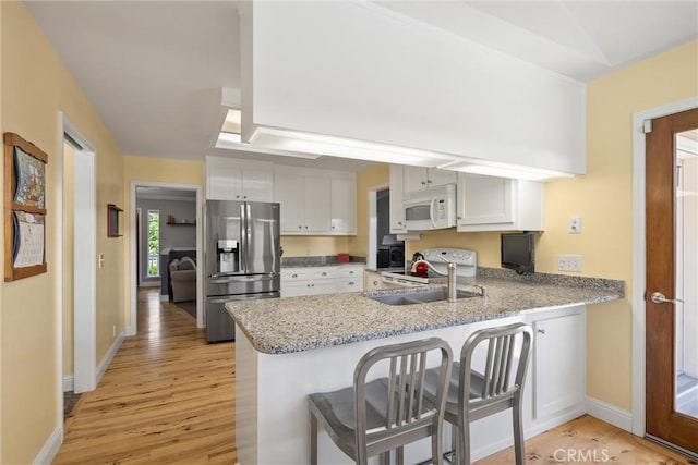 40 Gunter Ln, Oroville, CA 95966 - kitchen with white appliances, light wood-style flooring, a sink, and a peninsula