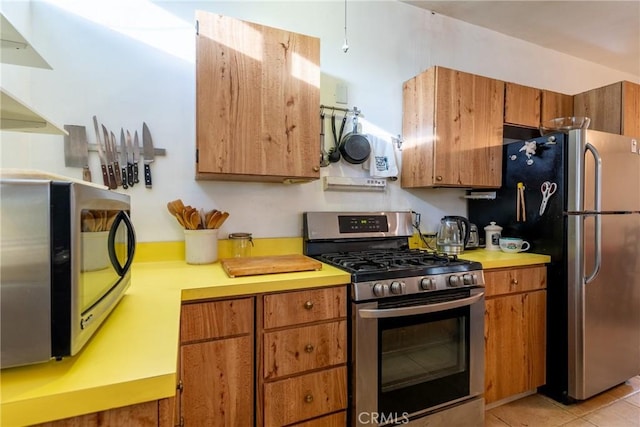 3956 Royce St, Riverside, CA 92503 - kitchen with appliances with stainless steel finishes, brown cabinetry, light countertops, and light tile patterned floors