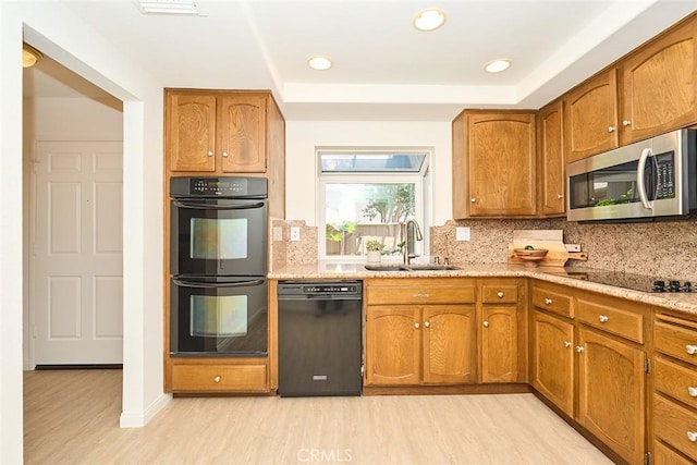 8068 Catherine Ave Unit 9, Stanton, CA 90680 - kitchen with black appliances, a sink, light wood-type flooring, tasteful backsplash, and brown cabinets