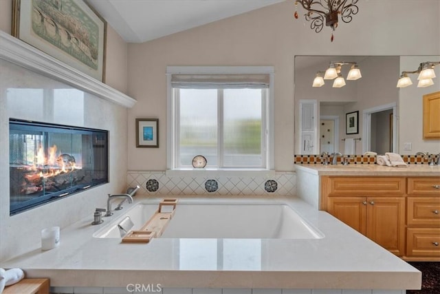 1304 Harkness St, Manhattan Beach, CA 90266 - full bathroom featuring a chandelier, lofted ceiling, a garden tub, vanity, and a glass covered fireplace