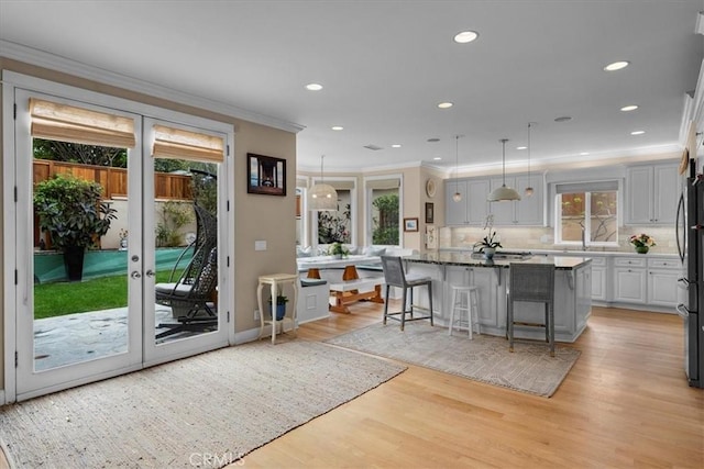 1304 Harkness St, Manhattan Beach, CA 90266 - kitchen with ornamental molding, a breakfast bar area, light wood-style floors, tasteful backsplash, and decorative light fixtures