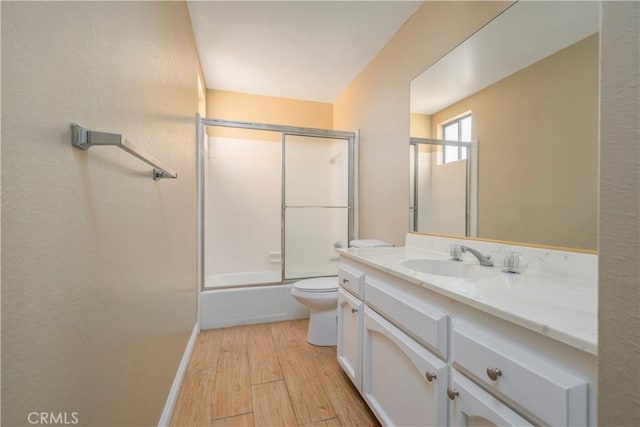 9403 Mesa Robles Dr, Whittier, CA 90603 - full bathroom with wood finished floors, toilet, vanity, shower / bath combination with glass door, and baseboards