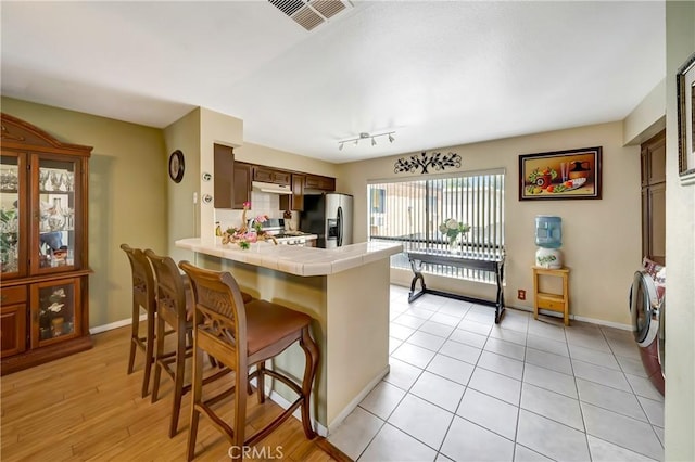 7226 Jordan Ave Unit 6, Canoga Park, CA 91303 - kitchen featuring independent washer and dryer, tile countertops, a breakfast bar, a peninsula, and stainless steel fridge