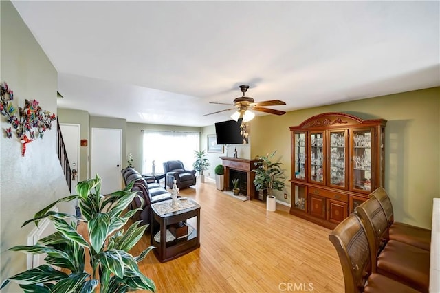 7226 Jordan Ave Unit 6, Canoga Park, CA 91303 - living area with a ceiling fan, a fireplace with flush hearth, light wood finished floors, stairway, and baseboards