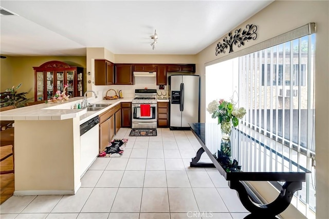 7226 Jordan Ave Unit 6, Canoga Park, CA 91303 - kitchen with appliances with stainless steel finishes, a sink, a peninsula, under cabinet range hood, and light tile patterned flooring