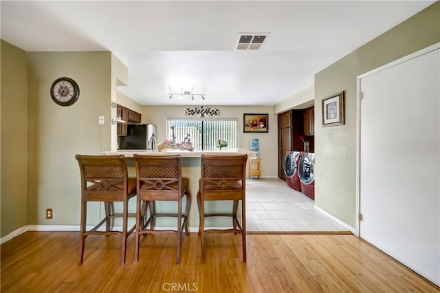 7226 Jordan Ave Unit 6, Canoga Park, CA 91303 - kitchen with washing machine and dryer, a peninsula, a breakfast bar, stainless steel fridge with ice dispenser, and light wood-style flooring